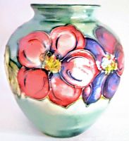 Front view of vase showing hand painted large red and purple flowers with yellow centers and green background.