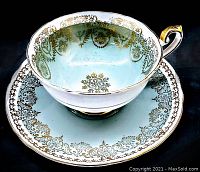 Photo showing the tea cup and saucer with detailed gold decoration and blue color under lighting