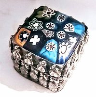 Angled view of the box showing colorful millefiori art glass lid and embossed silver sides