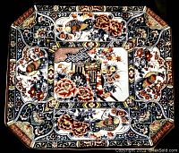 Top view of an octagonal vintage Asian platter hand painted with intricate floral and bird designs in black, brown, orange, and cream colors.