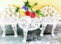 Front view of two chairs flanking round table with floral arrangement