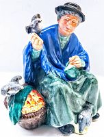 Front view of the Royal Doulton figurine showing an elderly lady seated, feeding birds with a basket of fruit beside her.