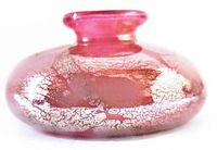 Close-up of pink glass bud vase showing metallic gold and reddish leaf pattern, narrow neck opening.