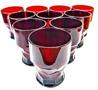 Seven ruby red tumblers arranged in a close group, showing faceted glass design and translucent coloring.