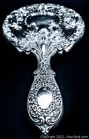 Close-up of the back side of the mirror's handle showing intricate floral and scroll patterns with an empty smooth cartouche space.