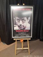 Full front view of framed poster on easel showing overall condition, frame and signature