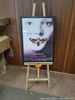 Full front view of framed poster on easel in a room