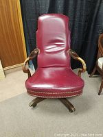 Front view of burgundy leather high-back swivel chair on wood base.