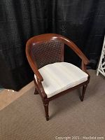 Front and side views of vintage wooden tub chair showing curved armrests, cane back, and cream upholstered seat cushion on carpeted floor.