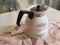 Blue cornflower CorningWare teapot with black handle and removable black lid, shown assembled.