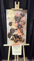 Full view of abstract painting on easel showing textured gold and coffee colored elements