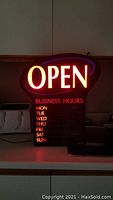 Illuminated view of the open sign showing 'OPEN' text in red and 'BUSINESS HOURS' with days of the week below in red.