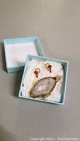 Crystal pendant and earrings displayed inside blue gift box with white tissue paper.