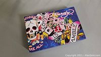Closed Ed Hardy box with tattoo-inspired artwork featuring skulls, hearts, and text design.