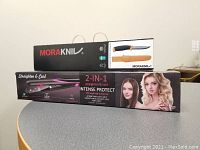 Two boxed items on a table: Mora Kniv hunting knife box with image of orange-handled knife, and 2-in-1 hair straightener and curling iron box showing female models and product labeling