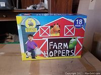 Front of the Farm Hoppers box showing a child playing on a gray bunny hopper toy, labeled for 18 months and up.