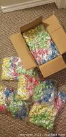 Photo of a cardboard box containing 5 sealed bags with individually wrapped pencil toppers in various colors.