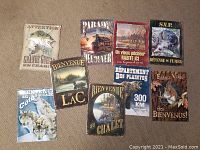 Photo displaying all nine tin wall signs in the lot arranged on floor.