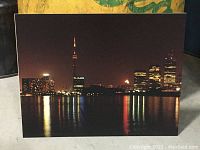 Front view of the vintage Toronto night skyline photo showing illuminated cityscape with CN Tower and reflections on water.