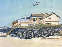 Watercolour painting showing a beige beach house on rocky coastline with sandy beach and three birds flying, framed and matted.