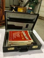 Open black attache case displaying a large stack of music sheets inside.