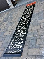 Full view of vinyl roll sign laid out on pavement showing all station names