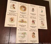 Front covers of all 11 miniature Beatrix Potter books laid out on table showing titles and illustrations