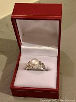 Sterling silver pearl ring displayed in open red ring box seen from top angle.