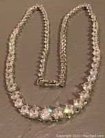 Full view of tennis-style necklace laid flat on surface showing overall length and design