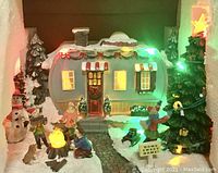 Photo of the LED holiday trailer village scene illuminated showing trailer, figures, tree, and snowman.