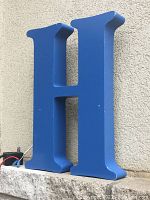 Front view of blue metal letter 'H' with visible minor paint scuffs and overall good structural condition.