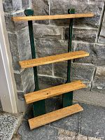 Front side view of wooden wall mount with four horizontal shelves supported by two painted wooden paddles.
