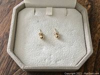 Pair of vintage 14K gold ball stud earrings displayed inside a white jewelry case with a soft cushioned interior.