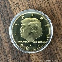 Front side of gold coloured coin showing Donald Trump's profile with 'LIBERTY', 'IN GOD WE TRUST', and '2020'.