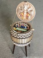 Open view of sewing basket showing contents of various sewing threads, scissors, needles and notions
