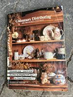 Front cover of the Consumers Distributing 1985/1986 catalogue featuring vintage home decor items in wood shelving.