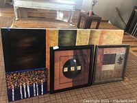 Four pieces including one large acrylic painting on canvas, two framed square artworks, and one smaller acrylic painting on canvas, arranged against a wooden floor.