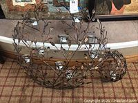 Both metal wall art votive holders shown on carpeted floor from top angle, detailing the integrated glass votive cups and metal branch structure.