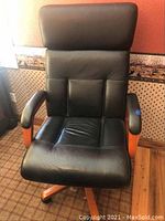 Front view of black leather office chair with pad and wooden armrests