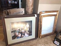 Photo showing multiple large wooden frames leaning against a wall, one containing a family photo.