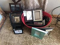 Red tub filled with 20+ small picture frames and additional frames arranged on floor