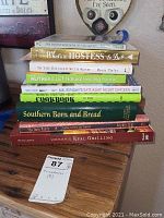 Photo of a stack of nine cookbooks showing titles and general condition.