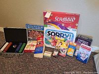 Photo showing the full selection of card and board games with most items still boxed or in packaging, and a metal briefcase containing poker chips.