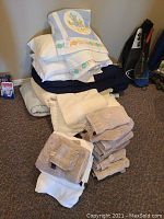 Stack of varied towels and bedding items, showing a quilt with floral applique on top.