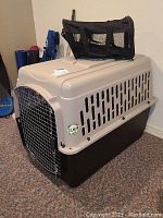 Large pet crate with metal wire door and ventilation slots on side, tan and black color