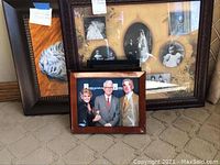 Five assorted wood picture frames of varying sizes with photos inside. Two large frames are at back, three smaller are at front on carpet.