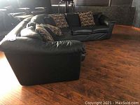 Large three-piece dark green leather sectional sofa shown in room with hardwood floor. Eight assorted throw pillows are on the sectional. Visible scratches and wear can be noted on the leather.