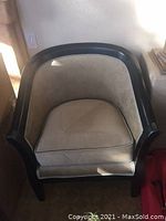 Photo of a single barrel style occasional chair with beige paisley upholstery and dark wood frame in a corner near a window.