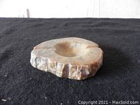 Side view showing the rough exterior of the stone ashtray and the shallow bowl with a cigarette rest.