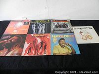 Seven assorted vinyl records laid out with visible cover art showing titles and artists for identification.